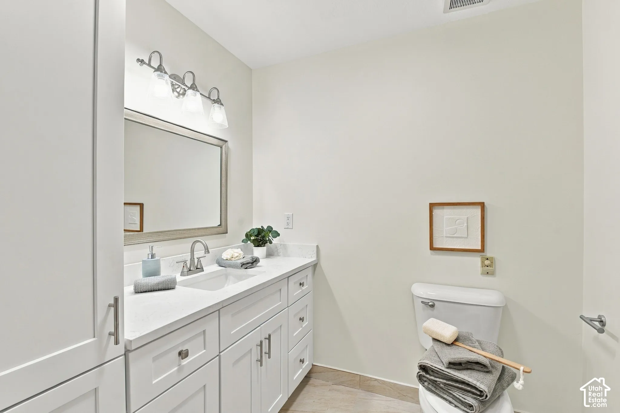 White vanity with ample storage, a single basin sink, and a countertop