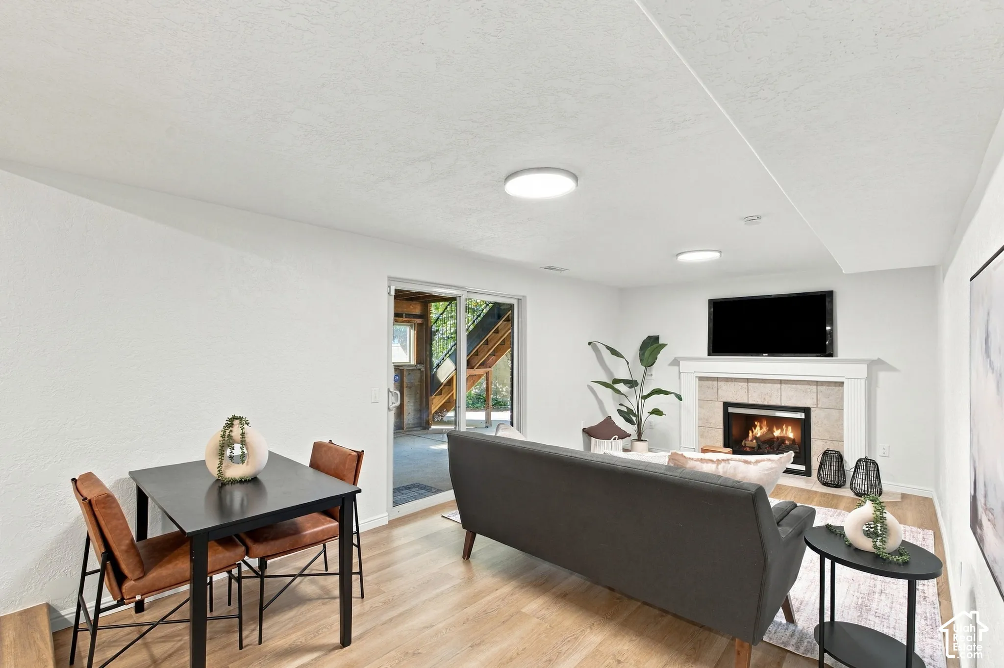 Recessed lighting, wood-finish flooring, stone-surround fireplace with mantel, and sliding glass door
