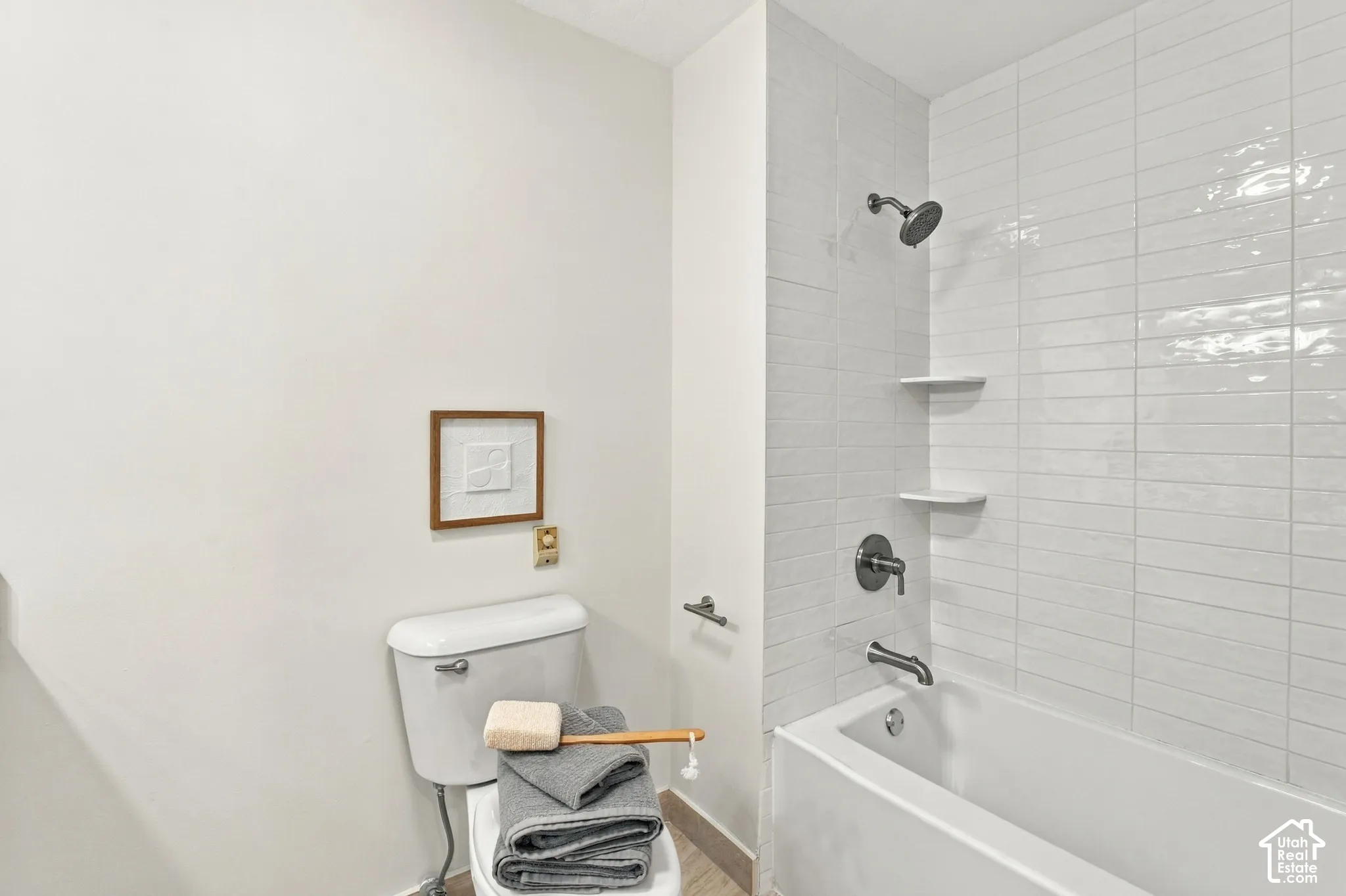 Tub and shower combination with white subway tile surround, matte black fixtures, and integrated shelving