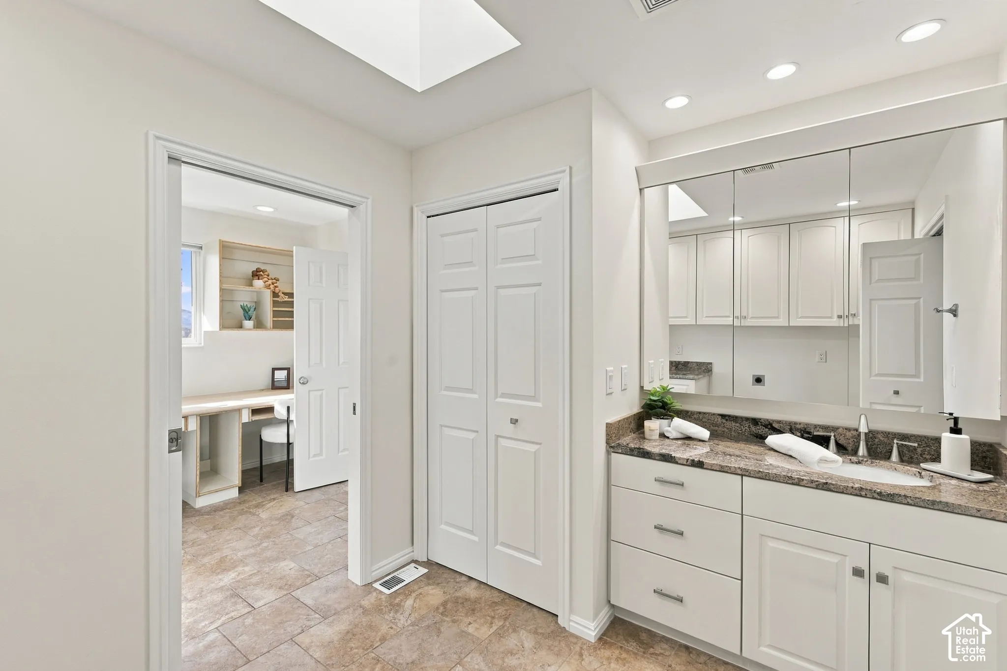 Vanity with a stone-finish countertop, undermount sink, and integrated cabinetry
