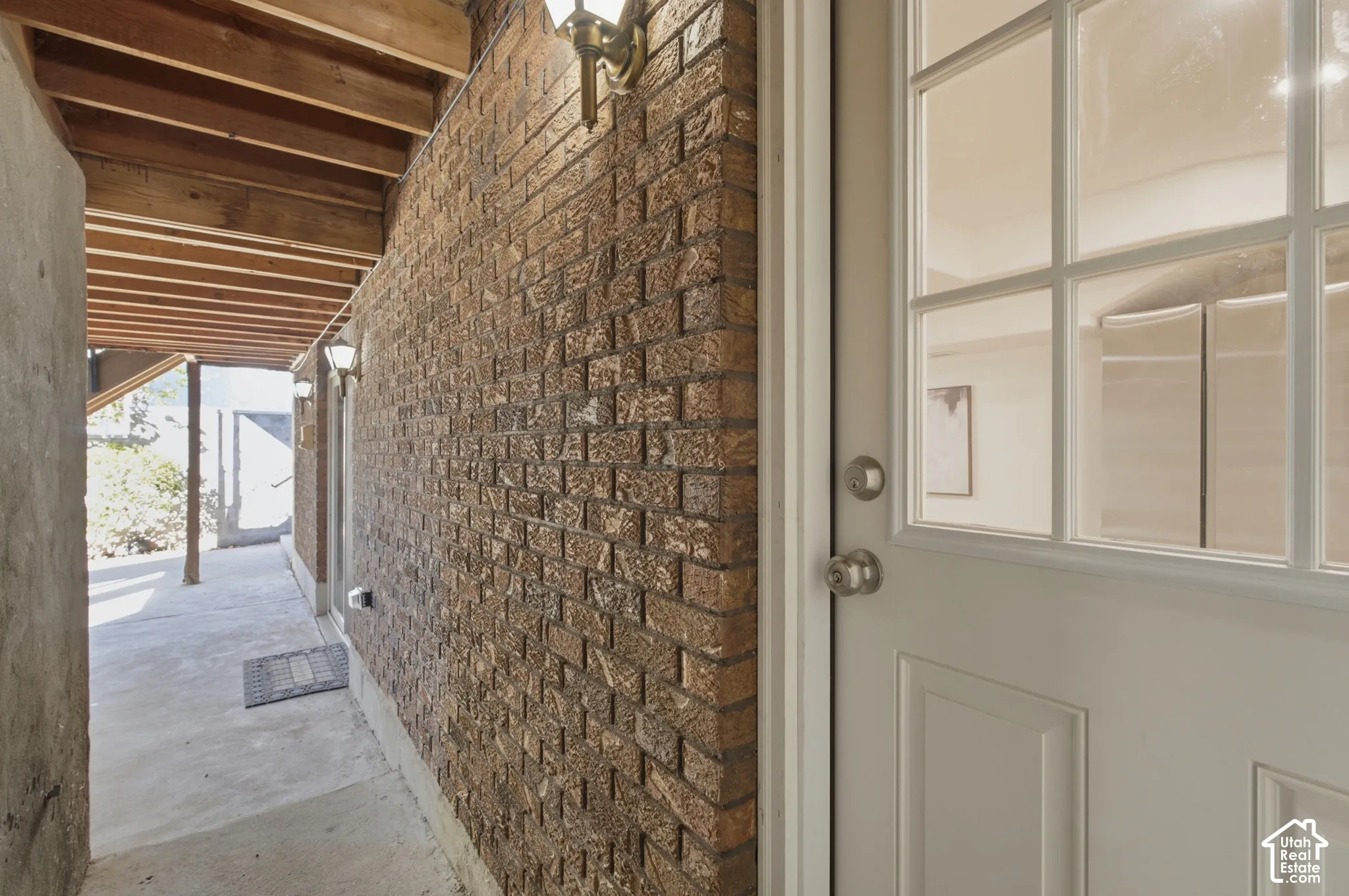 Exposed brick wall with sconce lighting and wood beam ceiling