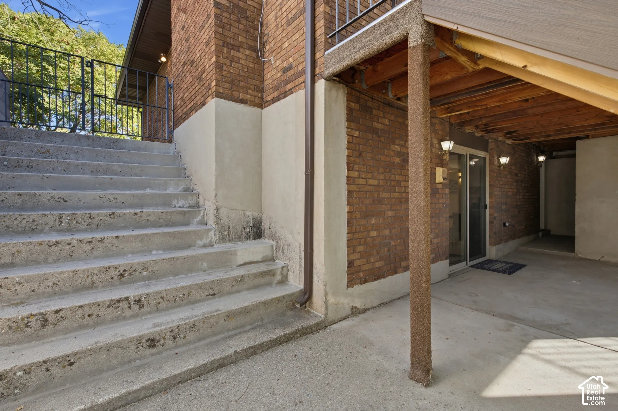 Brick exterior with concrete stairs, concrete patio, and sliding glass door entry