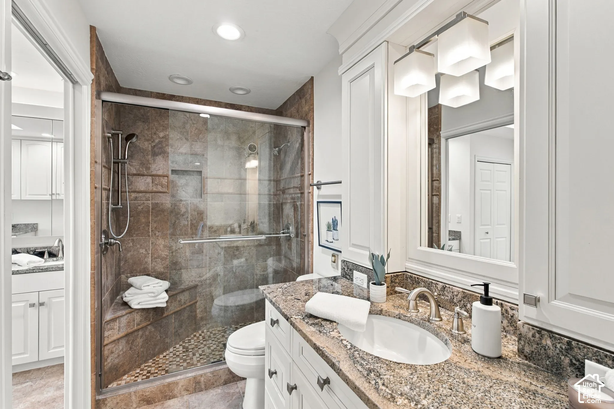 Walk-in shower with tiled walls and pebble floor, integrated bench, and clear glass enclosure