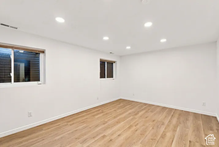 Recessed ceiling lighting, wood-finish flooring, and white painted walls