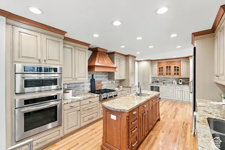 Gourmet kitchen featuring a center island, stainless steel appliances, light-toned cabinetry, wood-finish flooring, and recessed lighting