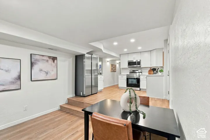 Kitchen featuring white cabinetry, stainless steel appliances, recessed lighting, and wood-finish flooring