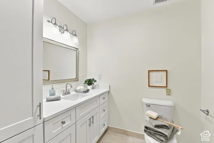 White vanity with ample storage, a single basin sink, and a countertop