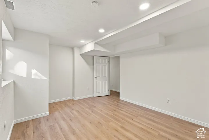 Recessed lighting illuminates the space, featuring wood-finish flooring and white painted walls