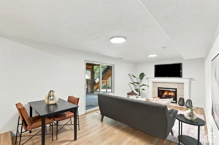 Recessed lighting, wood-finish flooring, stone-surround fireplace with mantel, and sliding glass door