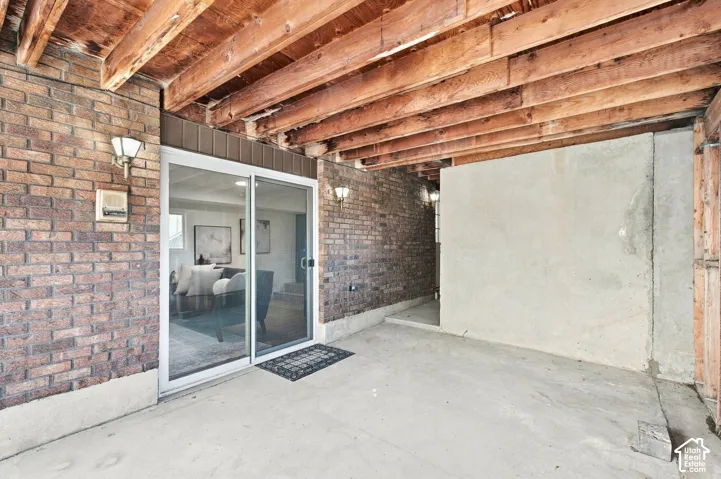 Concrete patio with exposed wood ceiling beams and brick wall accents