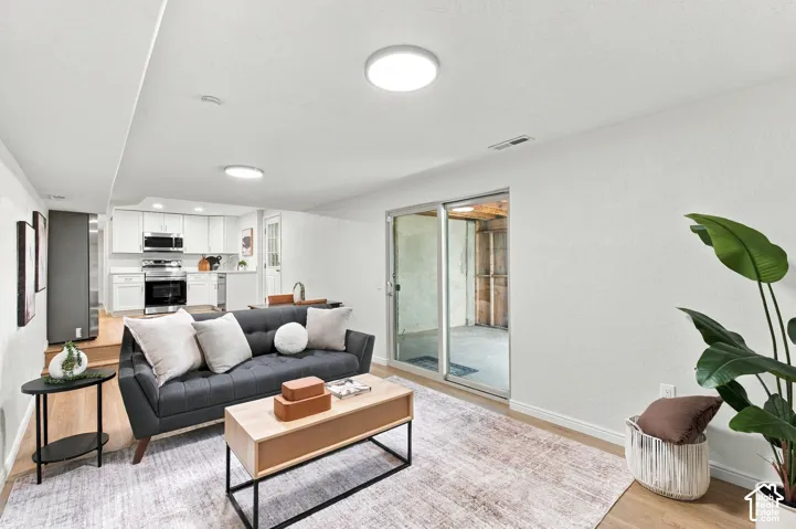 Open-concept living area featuring wood-finish flooring, recessed lighting, and a full kitchen with stainless steel appliances and white cabinetry