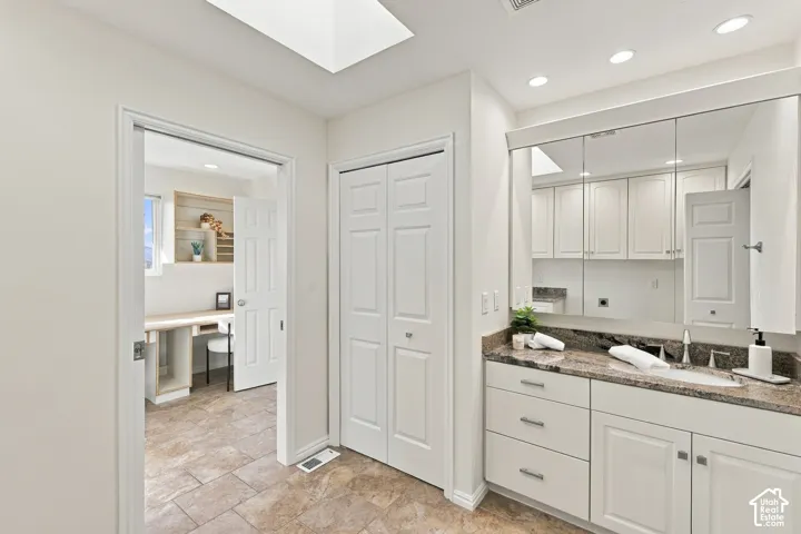 Vanity with a stone-finish countertop, undermount sink, and integrated cabinetry