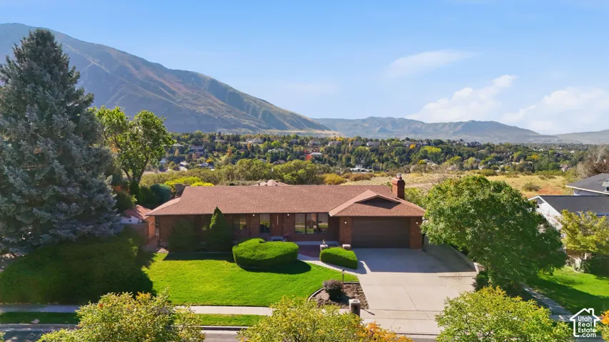 Stunning brick residence set on expansive grounds featuring manicured lawns, mature landscaping, and mountain backdrop