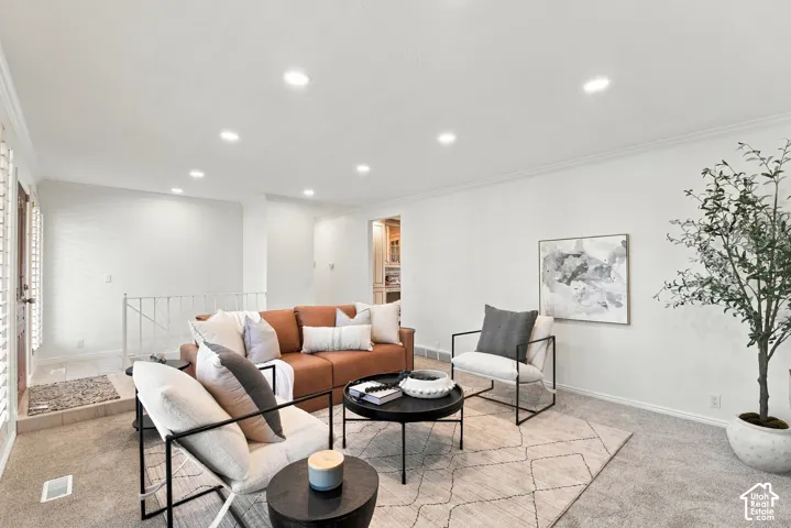 Recessed lighting, crown molding, white wall finishes, and light-toned carpeting create a bright interior