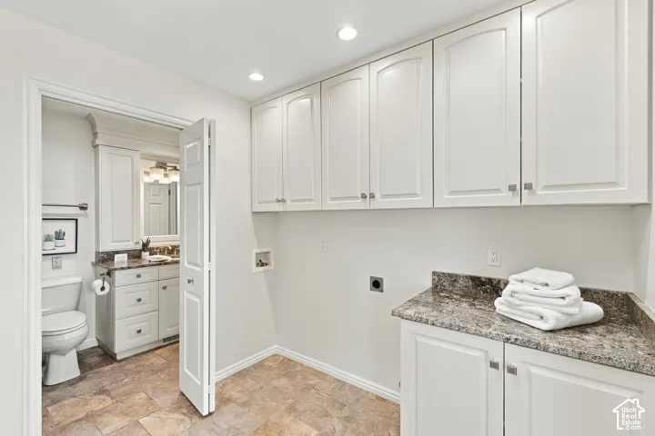 White shaker-style cabinetry, recessed lighting, stone-finish countertops, and tile flooring