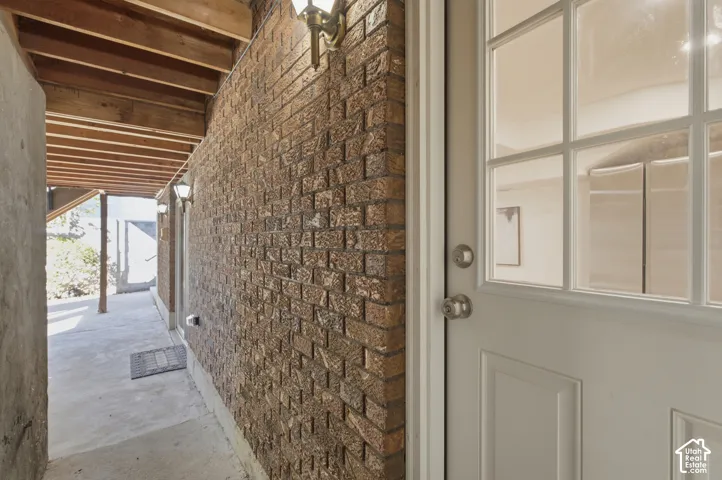 Exposed brick wall with sconce lighting and wood beam ceiling