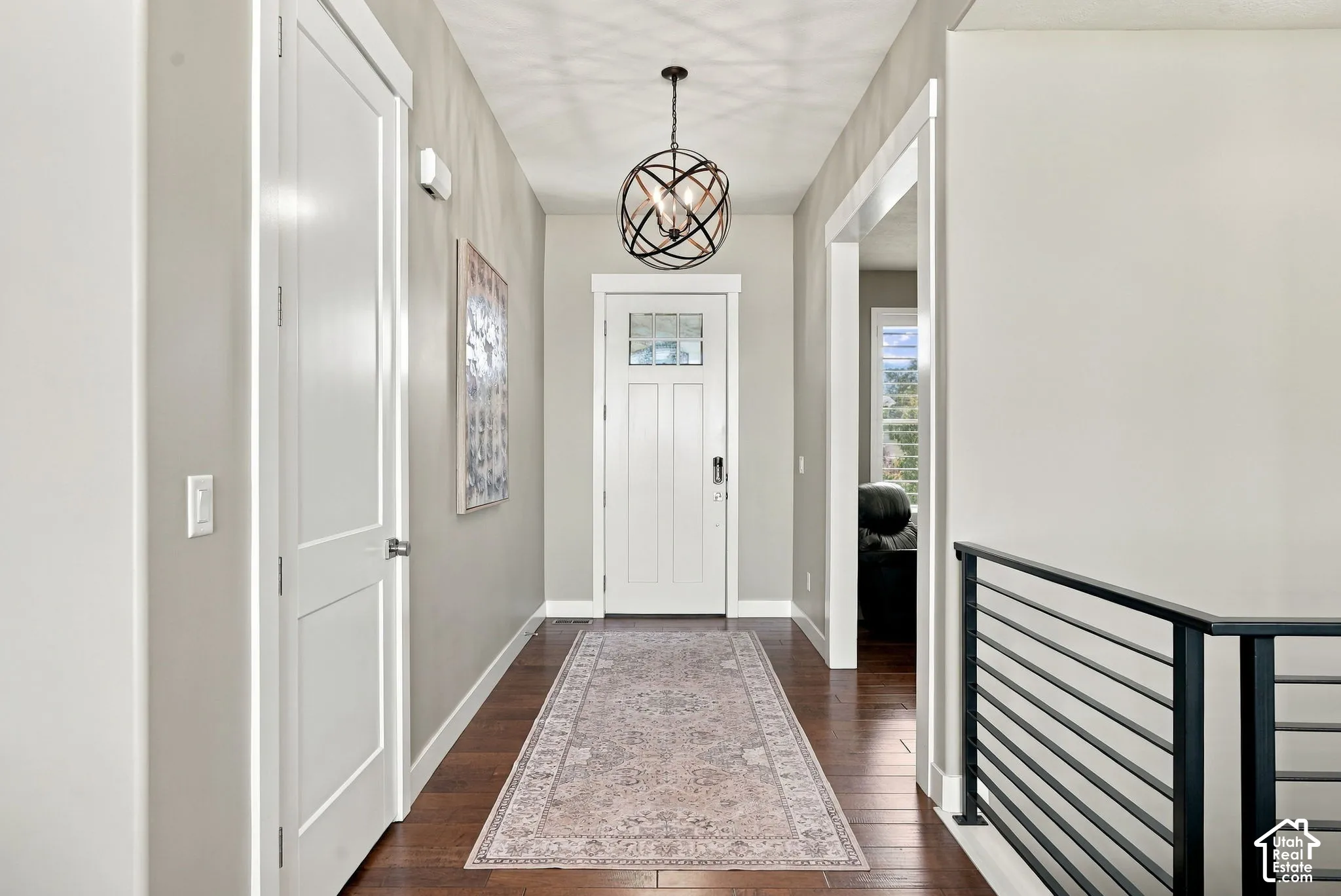 Front entry way, hardwood-style flooring throughout, contemporary pendant lighting, white interior doors, and a linear metal railing