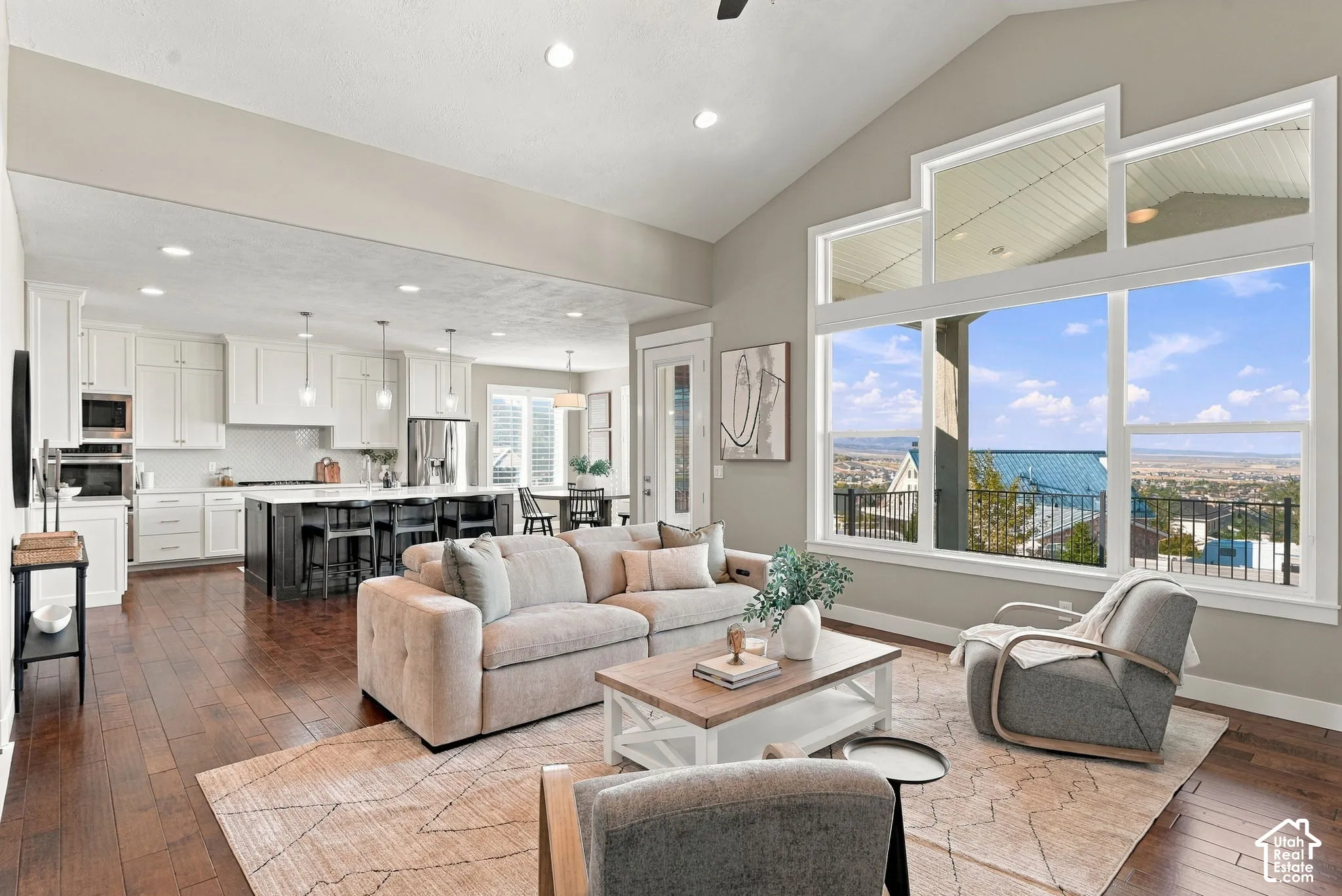 Living area featuring wood-finish flooring, vaulted ceilings, and expansive windows