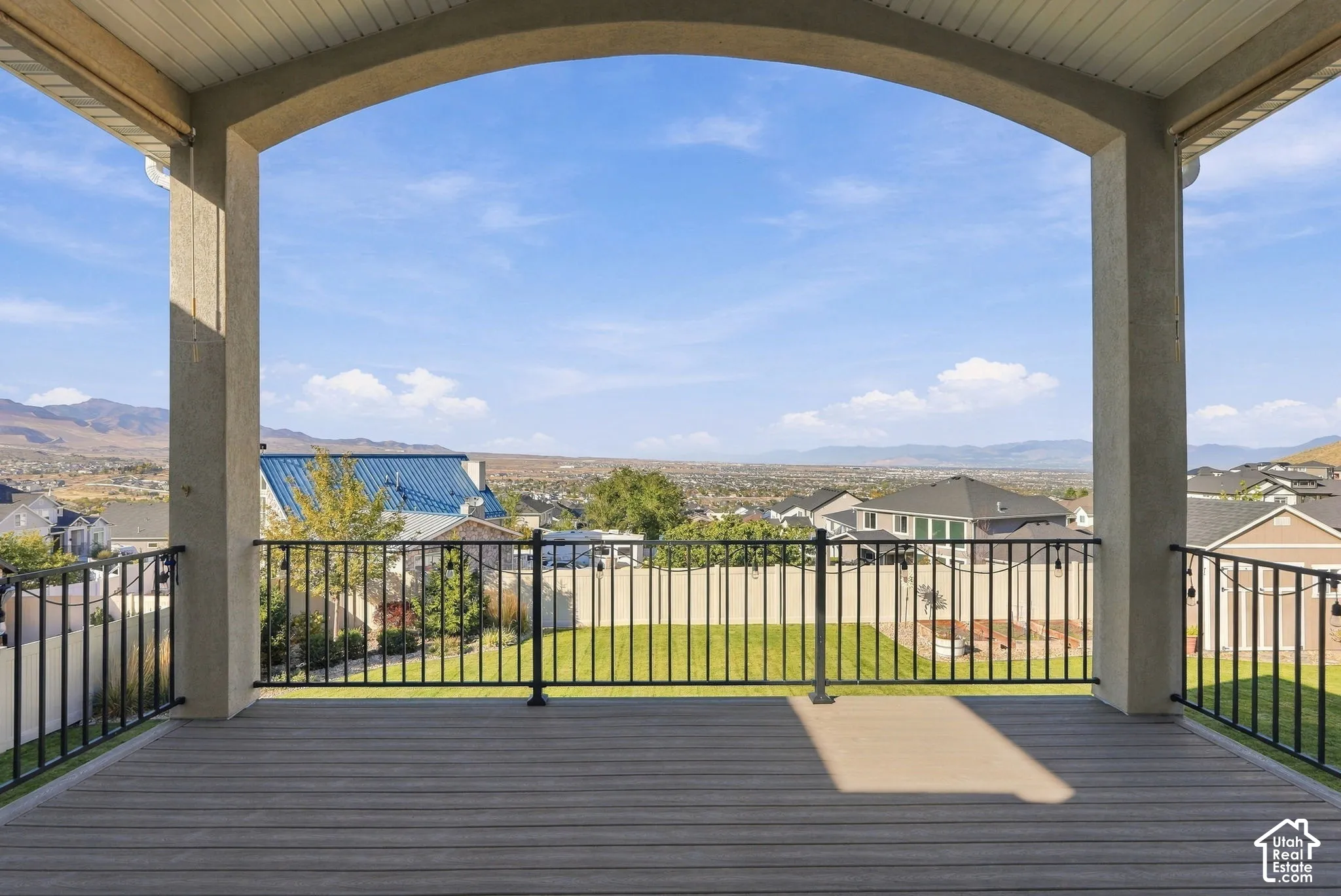 Archway-framed outdoor covered deck with composite decking and black metal railings
