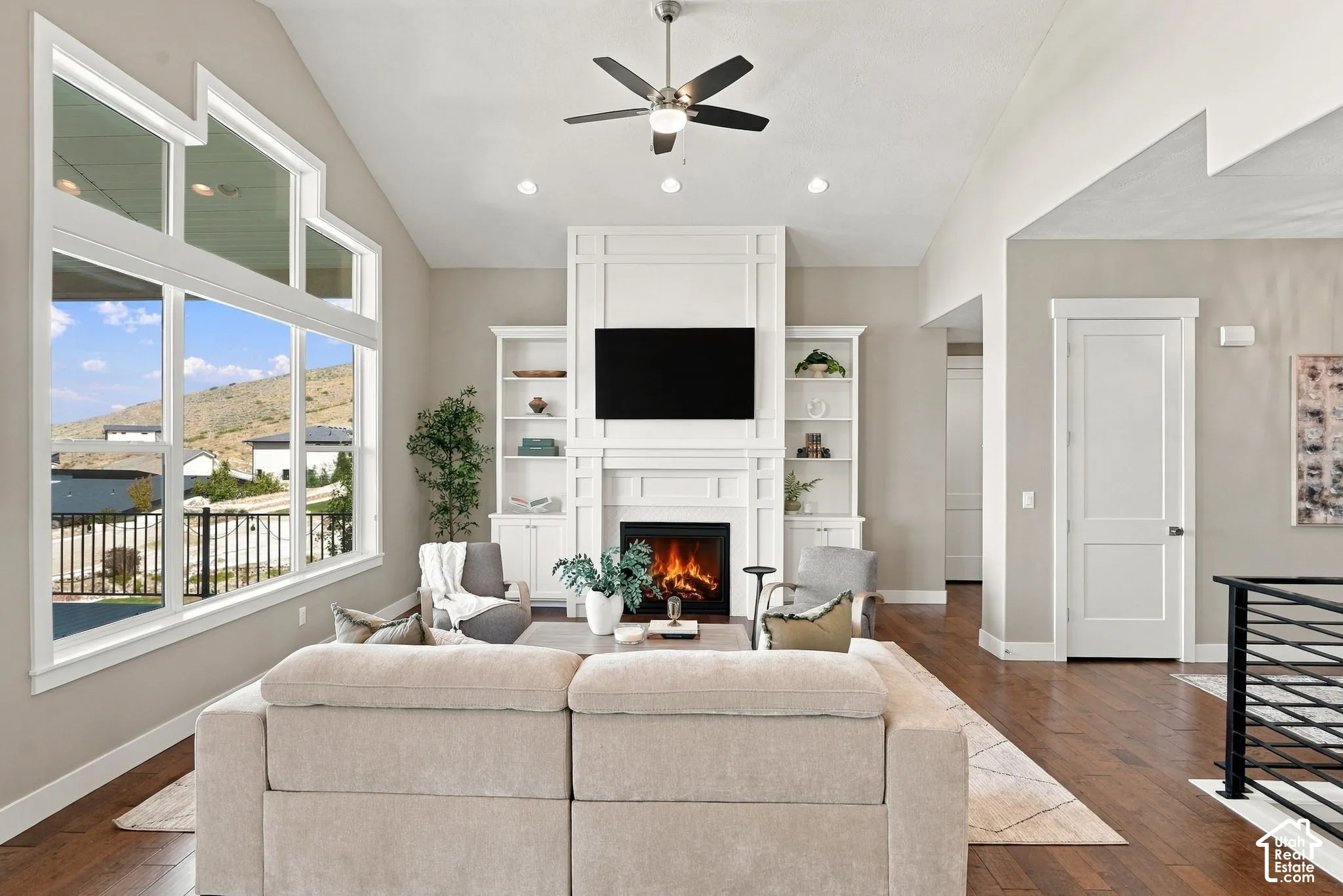 Vaulted ceiling with a ceiling fan, recessed lighting, and a prominent fireplace with built-in shelving