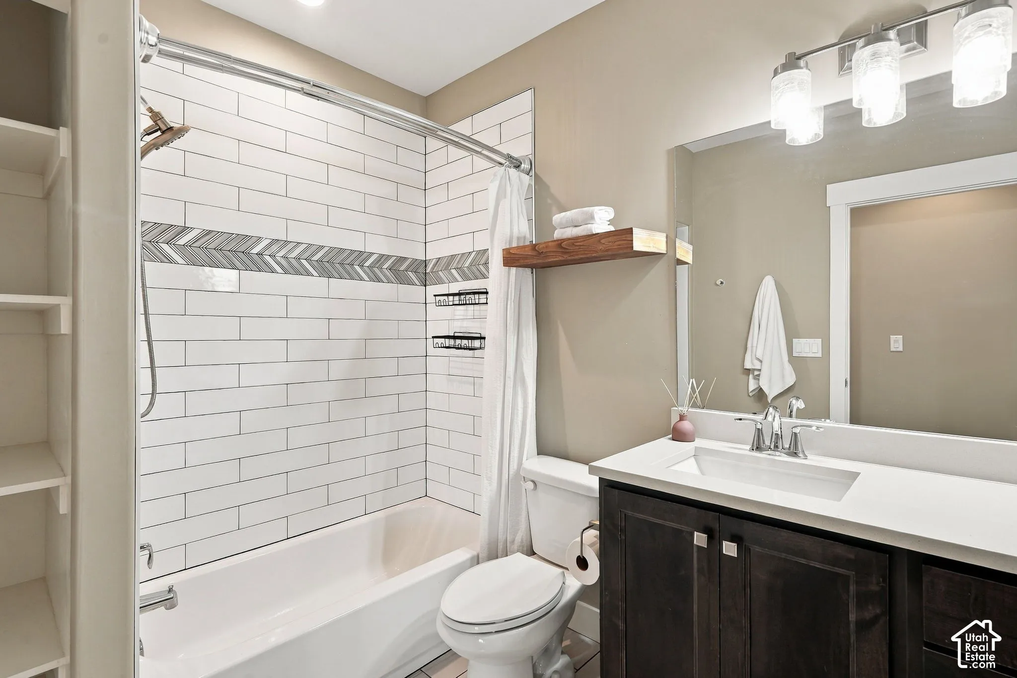 Basement bathroom four, Subway tile shower with decorative chevron accent, dark wood-finish vanity with a white countertop, and built-in shelving