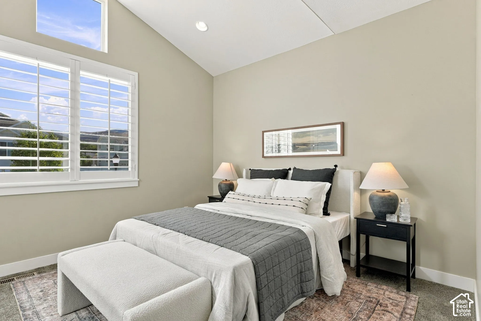 Main floor bedroom two, vaulted ceiling with recessed lighting, large window with plantation shutters, and an additional high window for natural light