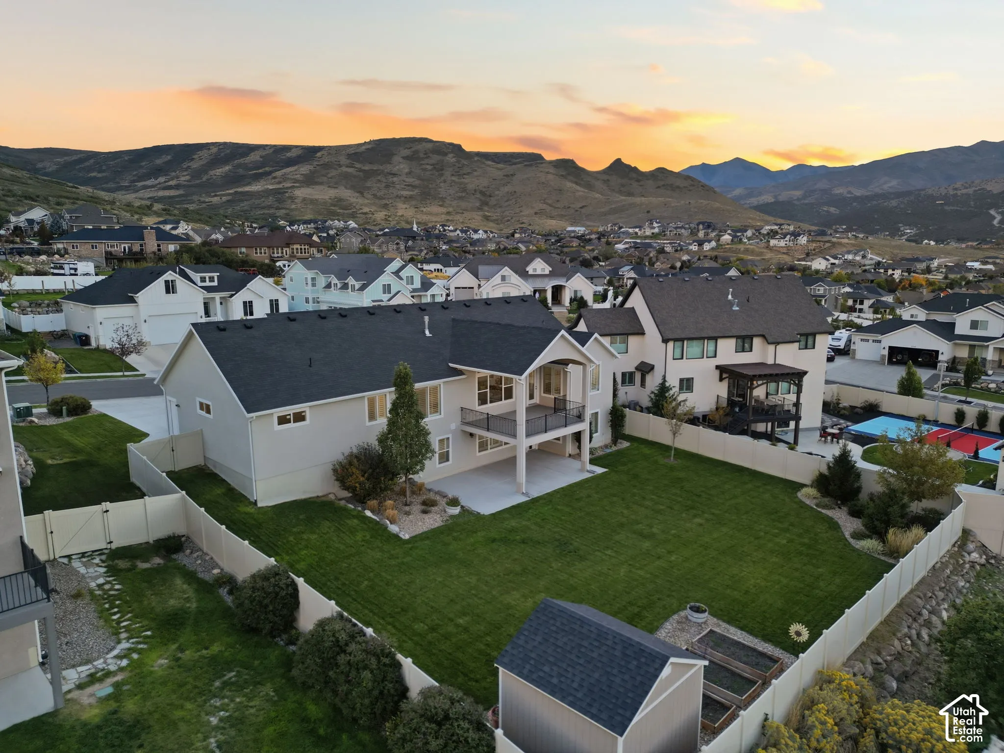 Expansive backyard featuring a manicured lawn, a concrete patio, and a multi-level deck with a metal railing