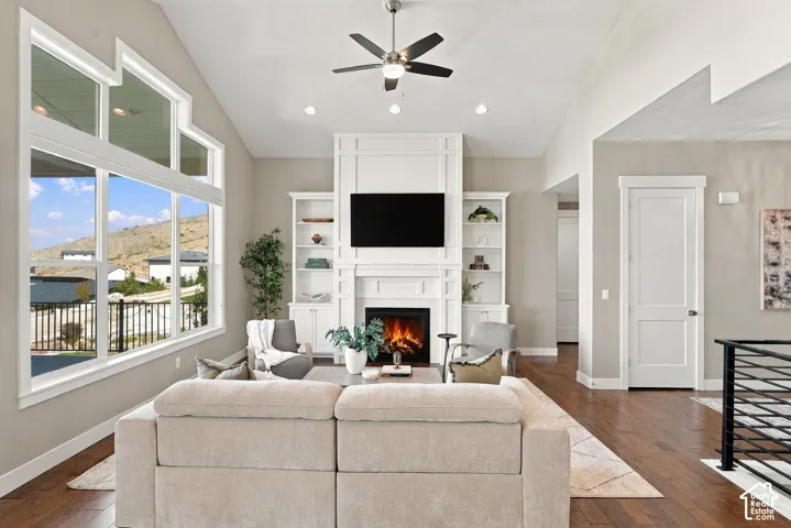 Vaulted ceiling with a ceiling fan, recessed lighting, and a prominent fireplace with built-in shelving