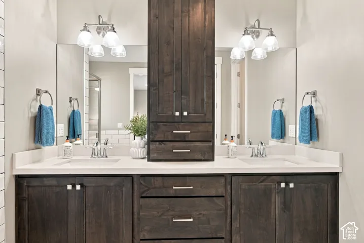 Primary bathroom with dual vanity with integrated sinks, light-toned countertops, and dark wood-finish cabinetry