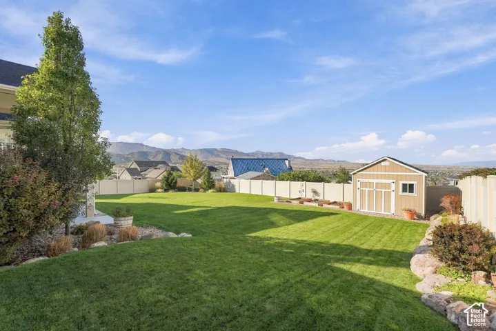 Expansive lawn with mature landscaping, a utility shed, and a privacy fence