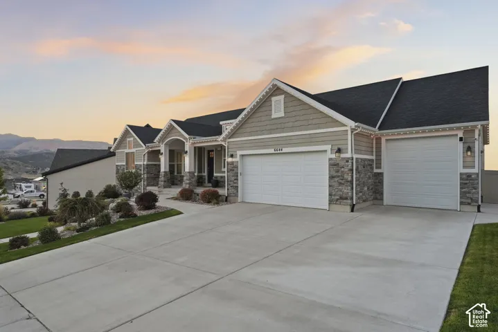 Multi-car driveway, attached three car garage, stone and siding exterior, front landscaping