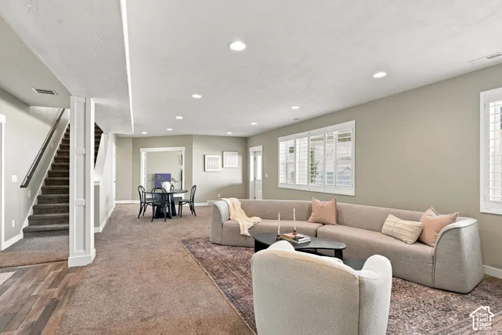 Recessed lighting, wood-finish flooring, staircase with dark handrail, plantation shutters, walk out basement, and light gray wall color