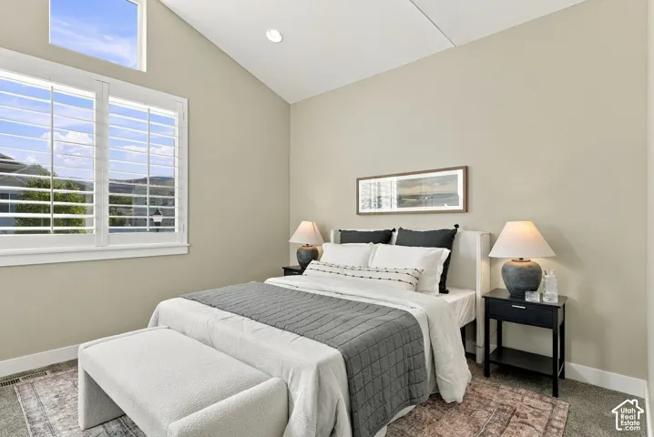 Main floor bedroom two, vaulted ceiling with recessed lighting, large window with plantation shutters, and an additional high window for natural light