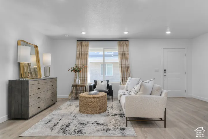 Recessed lighting, wood-finish flooring, white paneled door, and a prominent window with horizontal blinds