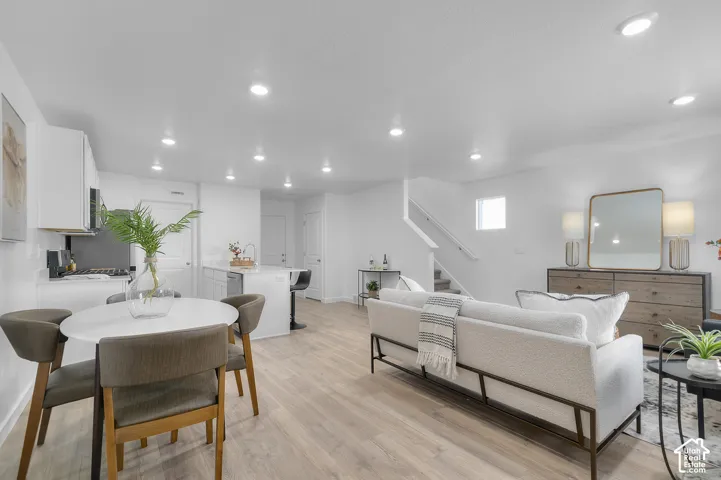 Recessed lighting illuminates the open-concept living space with wood-finish flooring
