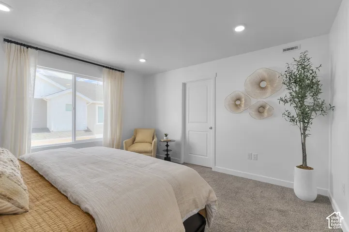 Recessed ceiling lighting, a large window with curtain rods, a white interior door, and light-colored carpeting