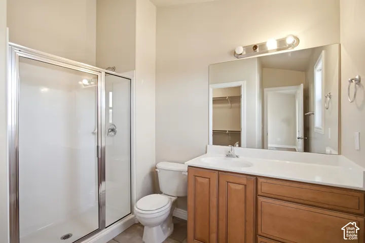 Walk-in shower with sliding glass door, single vanity with integrated sink, wood-finish cabinetry, and large wall-mounted mirror