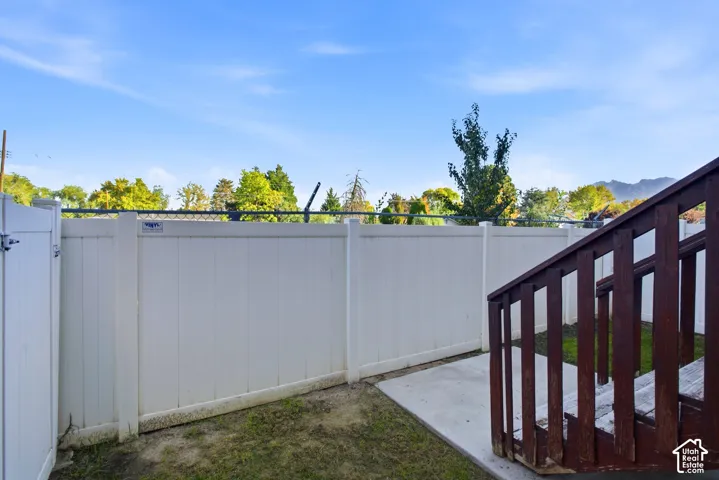 Private outdoor area featuring a white vinyl fence, concrete patio, and natural wood steps