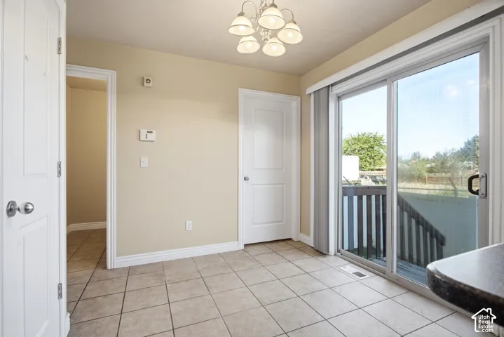 Tiled flooring, overhead lighting fixture, white interior doors, sliding glass door, and a partially visible dark countertop
