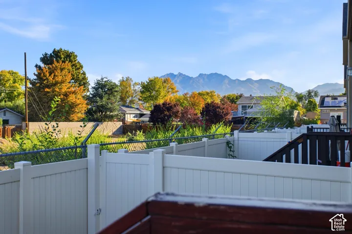 Expansive backyard oasis featuring white vinyl privacy fencing, mature landscaping with seasonal foliage, and mountain backdrop