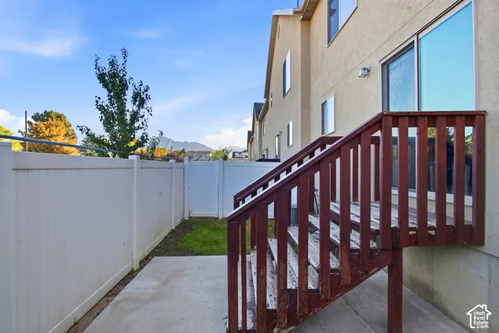 Exterior stucco finish, private fenced yard, concrete patio, sliding glass door, and exterior staircase