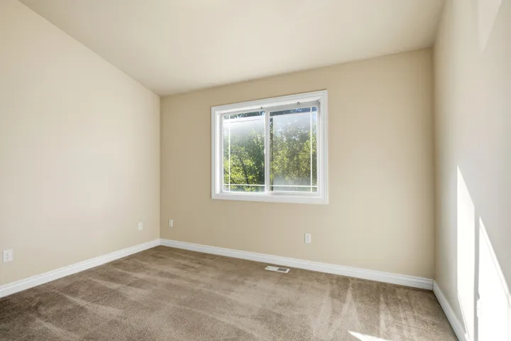 Neutral wall color, wall-to-wall carpeting, and a white-framed window