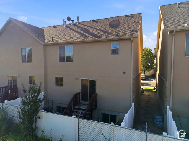Two-story residence with stucco exterior, multiple windows providing natural light, and a composite or asphalt shingle roof