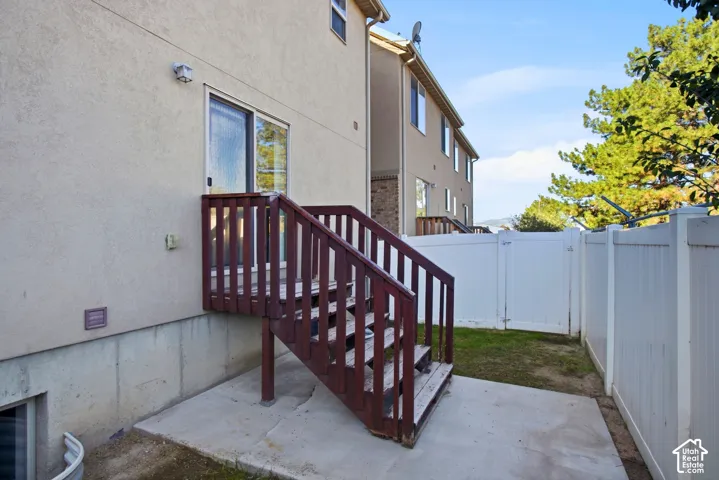Rear exterior with wood-finish stairs, sliding glass door, and concrete patio
