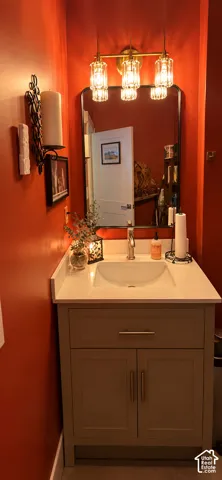 Vanity with a basin sink and brushed nickel faucet, quartz countertop, and recessed panel cabinetry