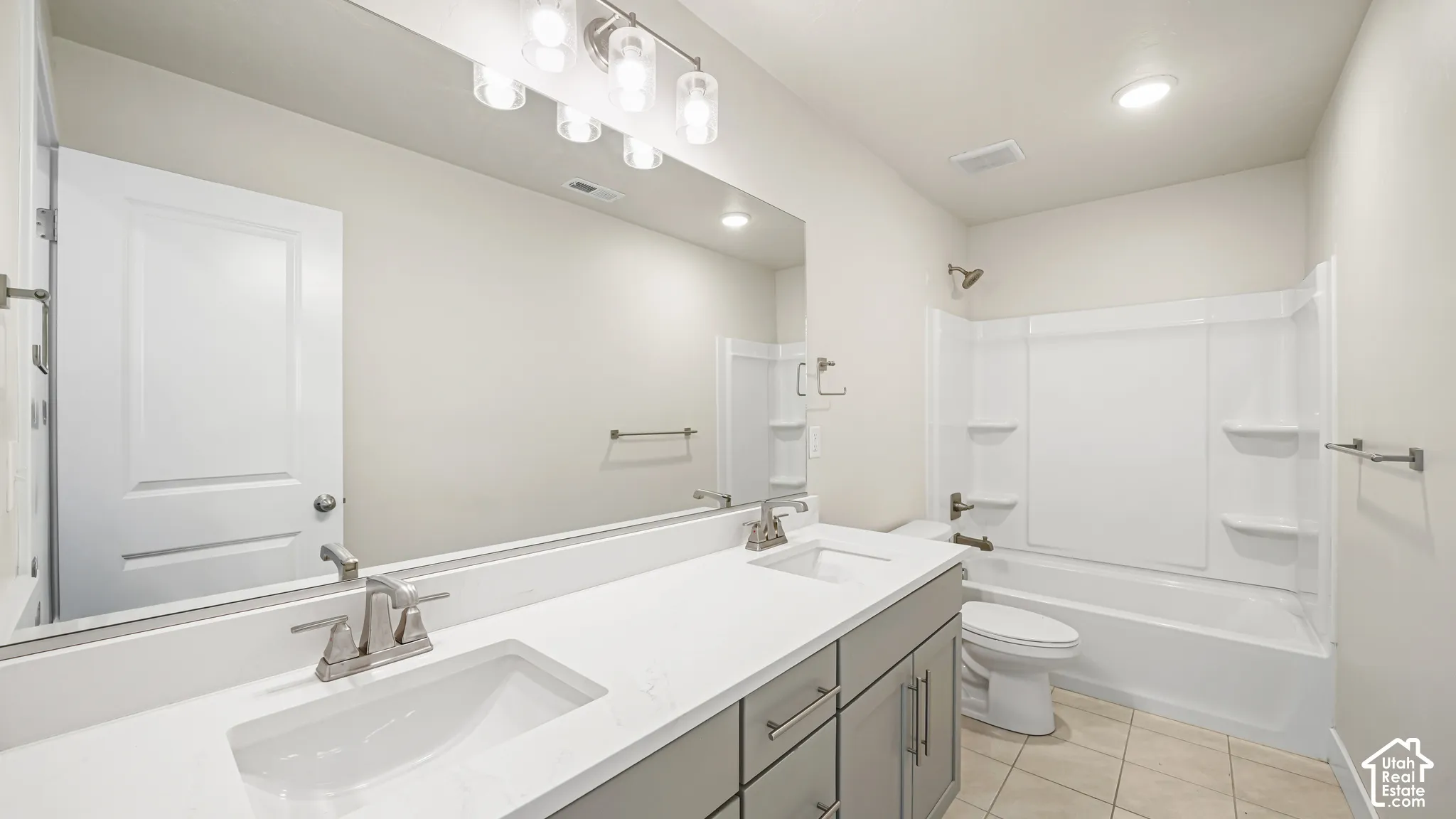 Dual-sink vanity with wood-finish cabinetry and white quartz countertops, paired with frameless mirror and polished nickel fixtures