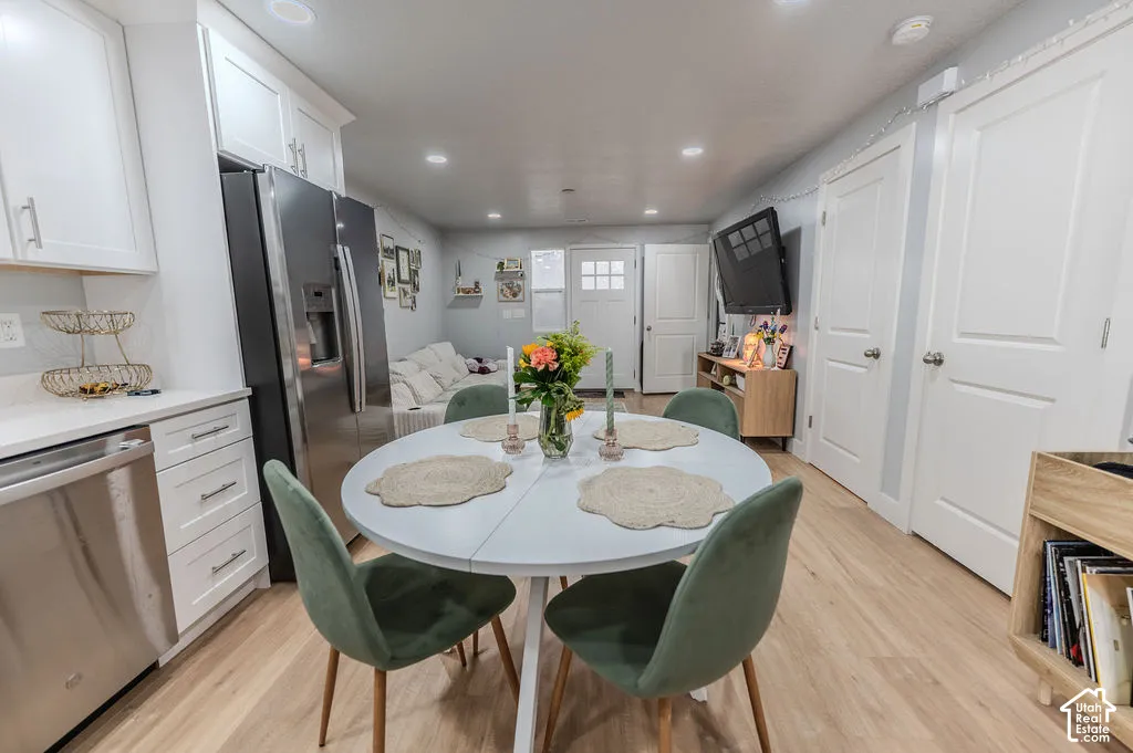 Open-concept living area with wood-finish flooring, white cabinetry, stainless steel appliances, and recessed lighting