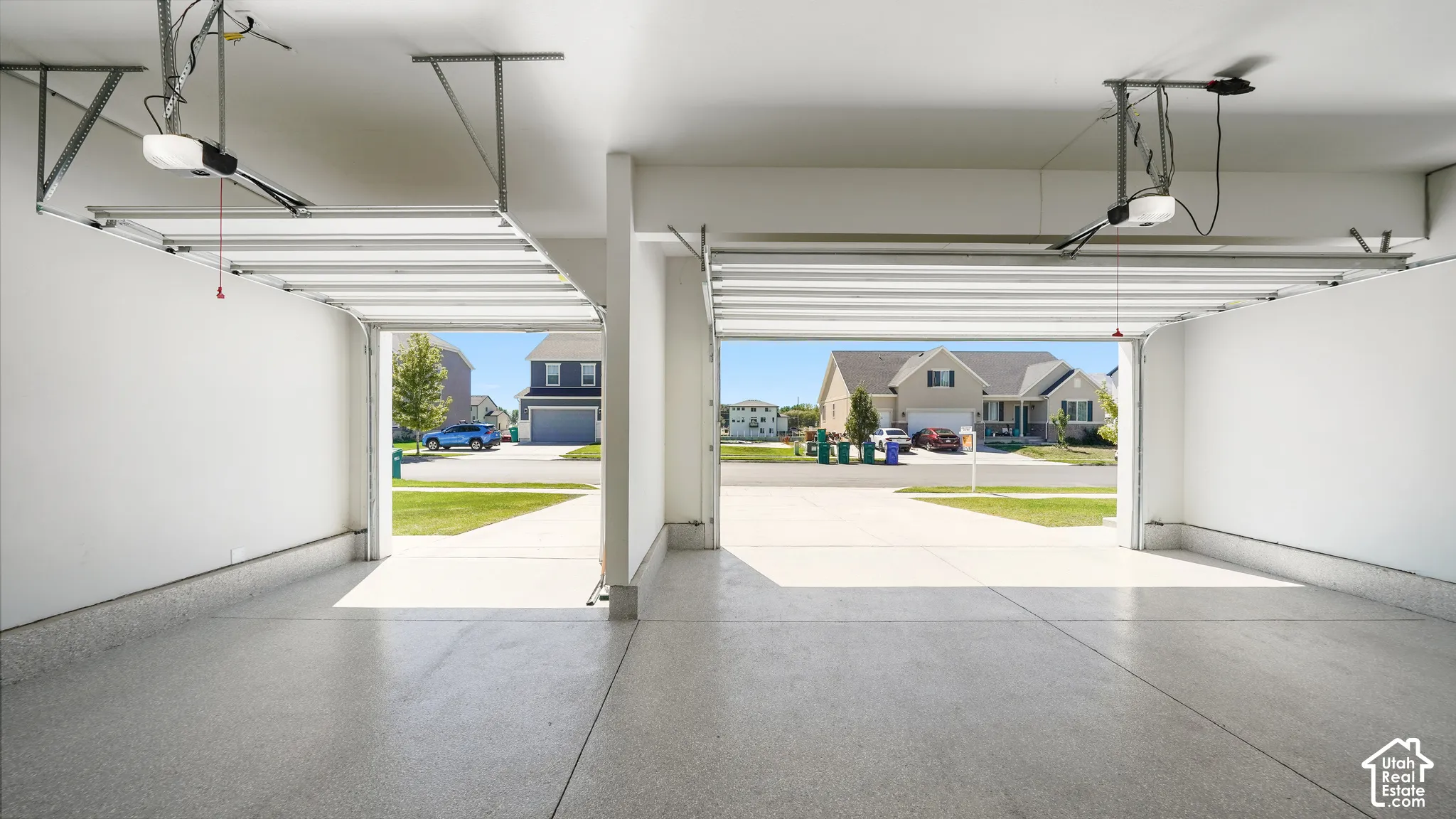 Two-car garage featuring automated door openers, clean white walls, and a durable epoxy-coated concrete floor