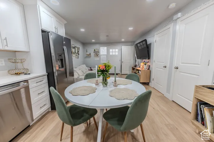 Open-concept living area with wood-finish flooring, white cabinetry, stainless steel appliances, and recessed lighting