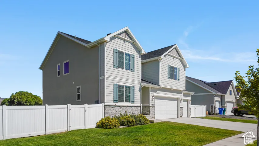 Two-story residence featuring light gray siding, decorative window shutters, and a stone accent facade